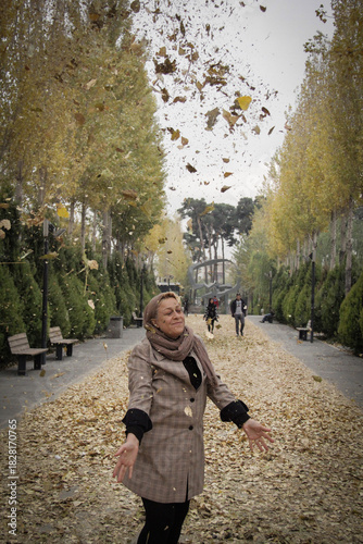 Wallpaper Mural A woman throws autumn leaves into the air in a park in Tehran, the capital of Iran Torontodigital.ca