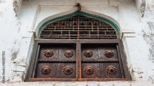 Ornate, aged wooden doors set in a whitewashed building