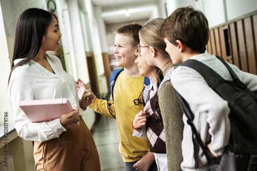 The teacher walks through the school lobby while talking with her students as class is about to begin. The moment feels relaxed and friendly, with everyone easing into the school day.