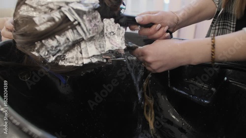 Colorist washes dye from hair to the sink