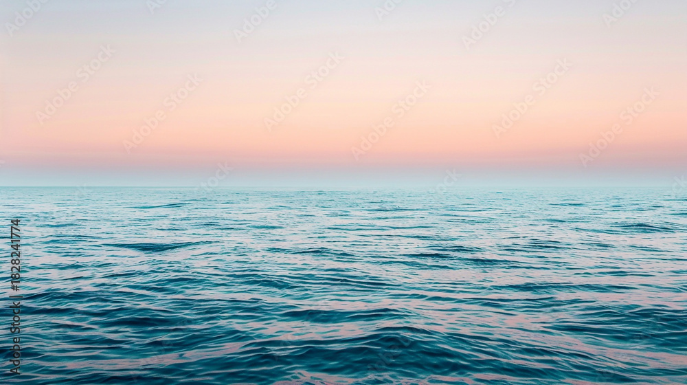 Obraz premium Calm ocean water with a pink and orange sky at sunset or sunrise
