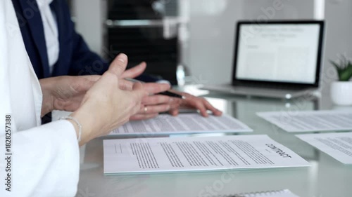 Businesspeople hands gesturing and reviewing contracts on a glass table during an important negotiation, concluding a deal in a professional corporate environment