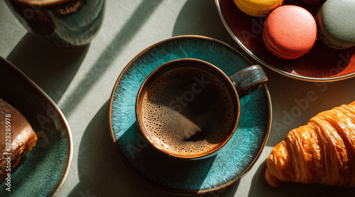 Strong Black Coffee in a Teal Ceramic Cup with Dramatic Shadows, a Golden Croissant, and Desserts on a Neutral Table in Bright Sunlight
