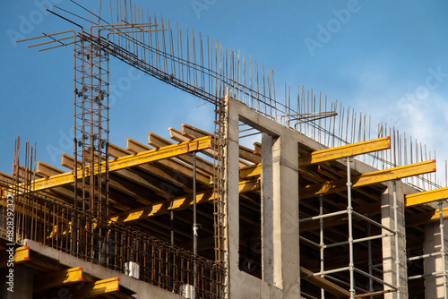 Monolithic Box under Construction with Yellow Volumetric I-Beams. Concrete Wall Frame Building with Formwork Prints and Rebar releases on Construction Site. Architectural origin Structure Sunny day.