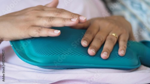 A person uses a heating pad on stomach for comfort and pain relief at home