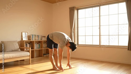 4k, Full shot of a young Asian man stretching his hamstrings in a sunlit room with minimalist decor, warm neutral tones, practicing yoga, achieving wellness indoors.