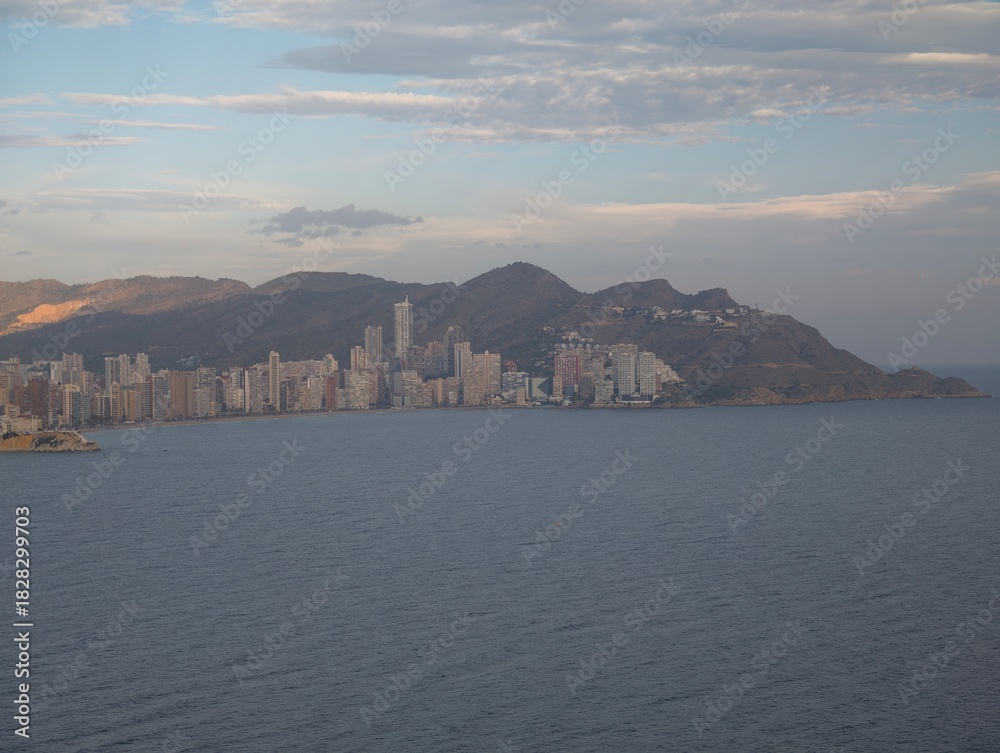 Fototapeta premium evening glow over urban shoreline, dusk casts amber light on metropolitan coastlines and peaks