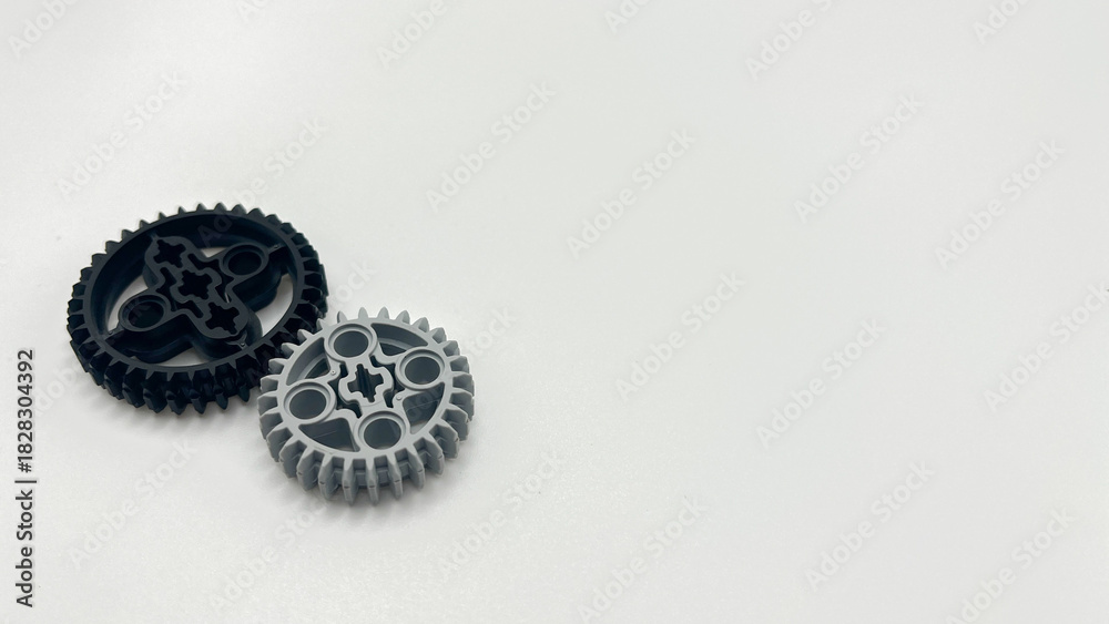 Fototapeta premium Black and gray plastic toy gears isolated on white background with copy space, mechanical concept