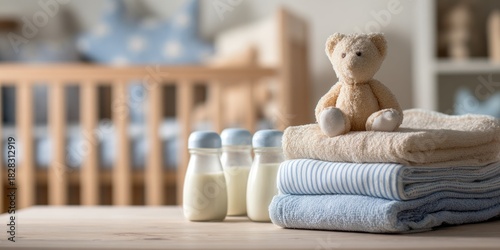 Baby essentials - bottles, blankets, and teddy bear on a table.