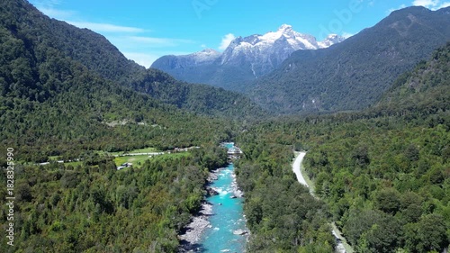 Hornopiren, Chile: Aerial footage of bridge and road by Rio Blanco surrounded by forest with mountain in the background in Hornopiren,  Chile's Los Lagos region along the Carretera Austral