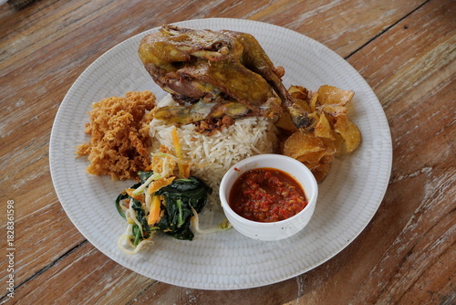 Asian lunch menu, white rice, fried chicken with chili sauce, complete with steamed vegetables served on a plate in a restaurant