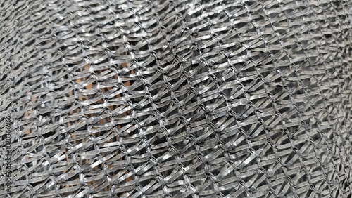Close up texture of woven black plastic mesh netting used for shade, agriculture, or construction safety fencing