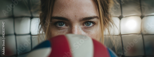Close up of focused young woman's intense eyes, partially obscured by volleyball