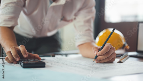 architect, engineer, engineering, architecture, design, plan, plans, construction, An engineer reviews construction blueprints while making calculations and notes on the design.