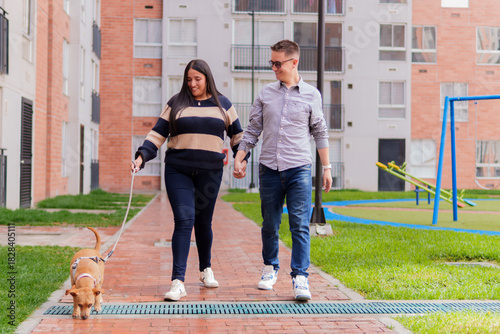 Couple walking dog and holding hands in urban park