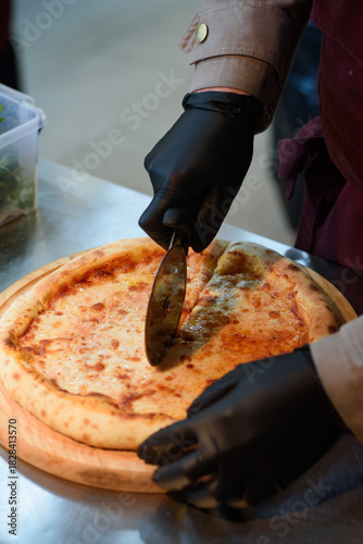 The pizza chef cuts the pizza into equal pieces