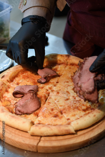 The pizza chef puts the finished meat on the finished pizza