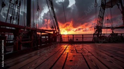 A dramatic sunset view from the deck of an old wooden sailing ship.