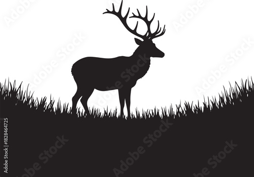 Black silhouette of a stag with large antlers standing in grass
