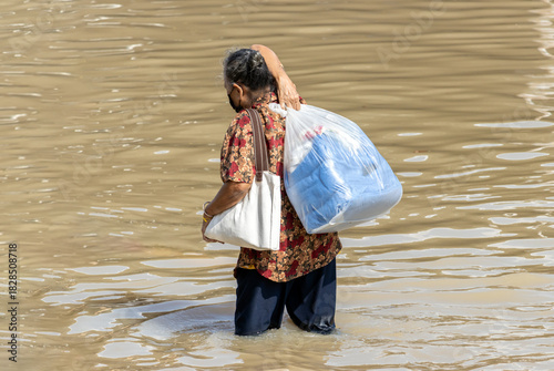 A woman with a big bag wades through a flooded street, Bangkok, Thailand