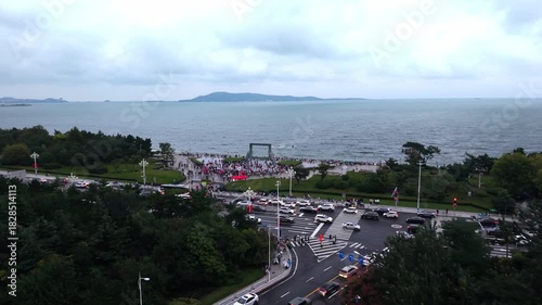Busy seaside promenade and iconic wave sculpture plaza at sunset, aerial China
