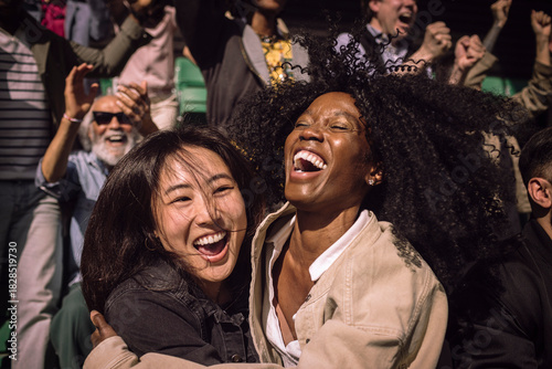 Carefree female friends celebrating with each other in stadium stand on game day