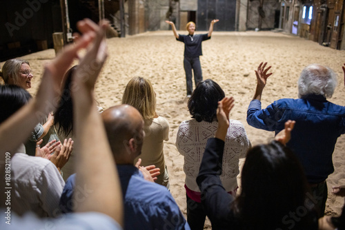 High angle rear view of male and female spectators giving standing ovation to performer after play in theater