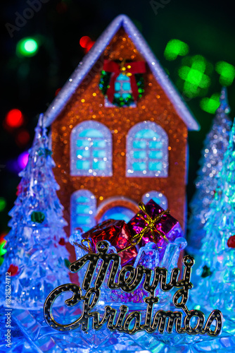 Close-up of glass Christmas trees with presents in a stand and letters in front around an orange house