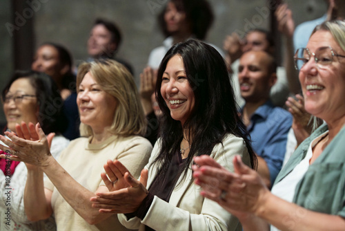 Smiling mature woman giving standing ovation in stage theater