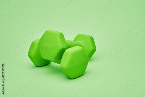 Two bright green dumbbells stacked together on solid background for fitness and exercise concept