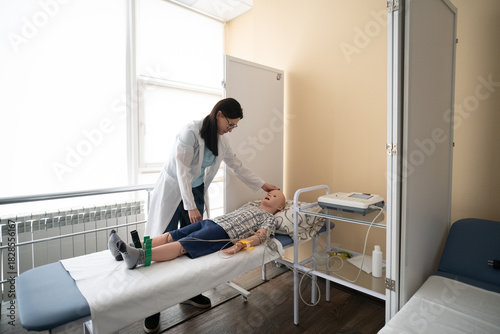 Billede på lærred Medical student in a white coat conducting a simulated patient examination on an