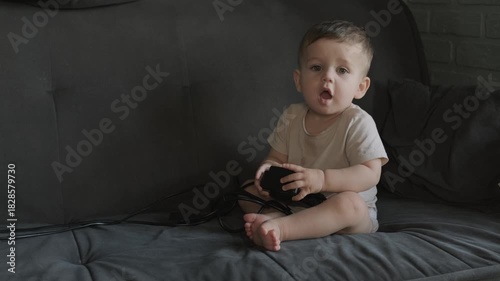 Wallpaper Mural The little one year old baby is sitting on the sofa and holding something in his hands
 Torontodigital.ca