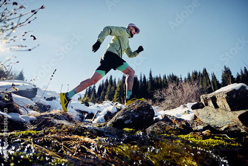 Man running trough the river in the winter mountains
