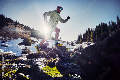Man running trough the river in the winter mountains