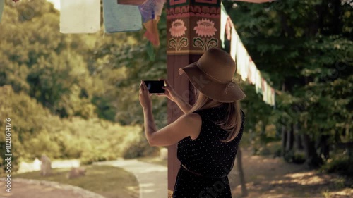 Female Tourist Capturing Buddhist Style Garden with Colorful Prayer Flags