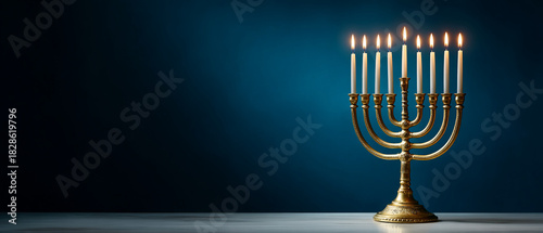 A golden menorah with nine lit candles against a dark blue background