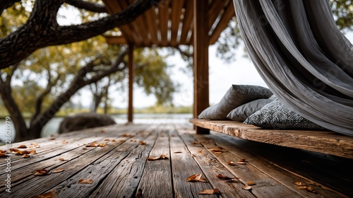 Cozy wooden terrace with flowing white curtains and green plants in soft sunlight.