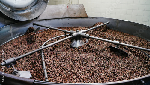 coffee roasting machine stirring fresh beans inside the large metal drum at an industrial facility