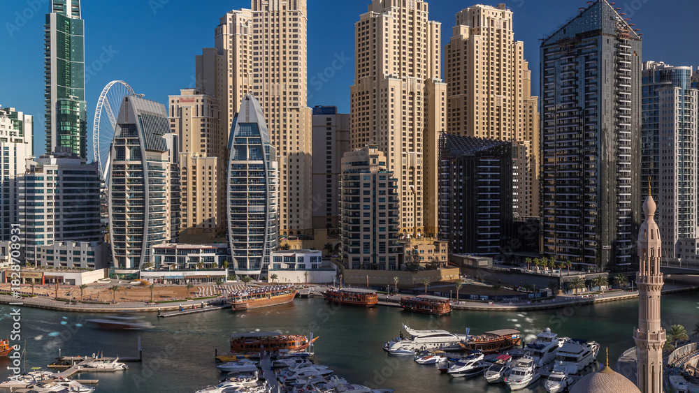 Fototapeta premium Luxury yachts parked on the pier in Dubai Marina bay with city aerial view timelapse