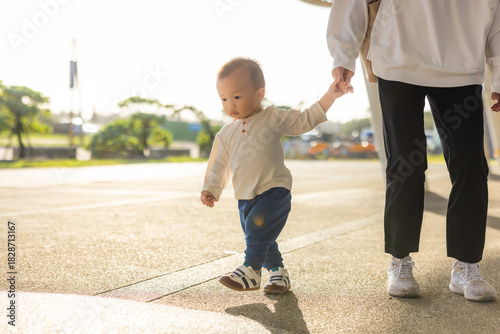 Mother walking with her baby holding hands outdoors
