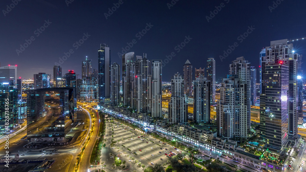 Obraz premium Modern residential and office complex with many towers aerial night timelapse at Business Bay, Dubai, UAE.