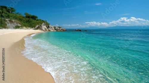 Soft sandy beach stretches along a calm ocean with clear turquoise water under a bright blue sky. Gentle waves lap at the shore creating a tranquil atmosphere.