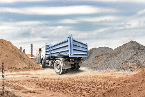 Canvas Print A truck is unloading materials at a construction site filled with piles of sand
