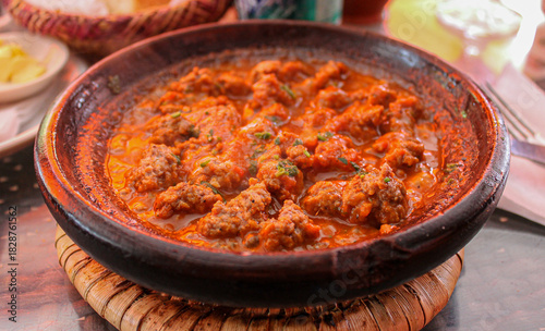 Marrakech, Morocco. Earthenware bowl with kefta tagine showing spiced meatballs in tomato sauce, a traditional Maghrebi dish prepared with herbs and slow cooked in a clay vessel