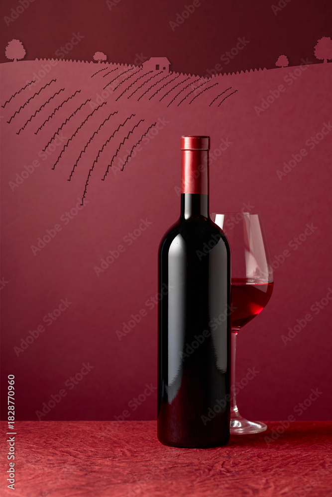 Fototapeta premium Bottle and glass of red wine on a red background.