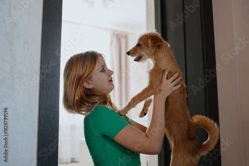 A 12-year-old teenage girl plays and laughs joyfully with her dog. Authentic moment of teen-pet bonding, pure happiness and carefree friendship