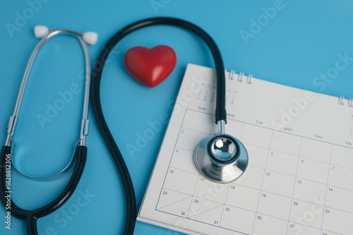 Fotografie Stethoscope and red heart on calendar over blue background for medical appointment concept, health check-up schedule, annual physical exam reminder