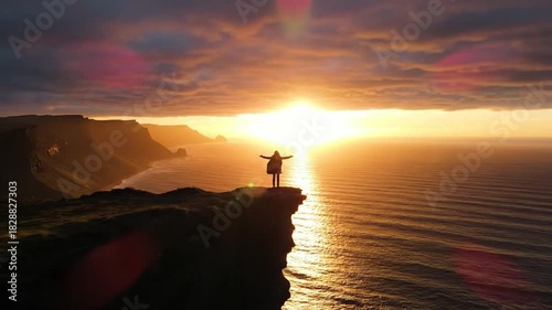 Human figure standing on cliff edge at sunset overlooking vast ocean landscape