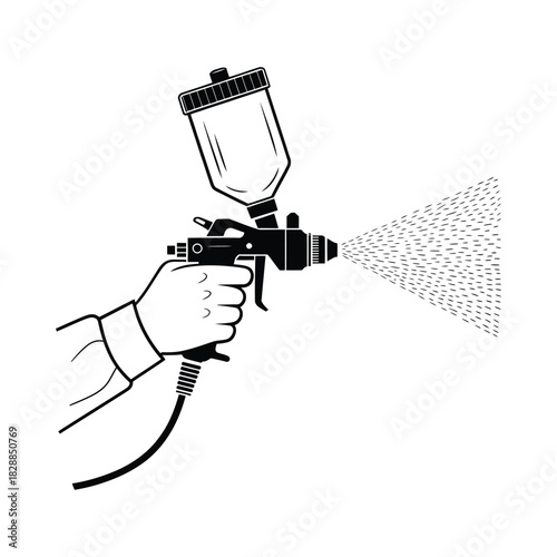 Hand holding spray gun applying paint in a fine mist