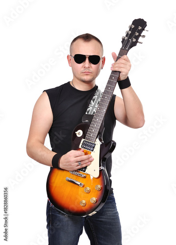 Roker in jeans and a T-shirt wearing dark glasses plays an electric guitar.